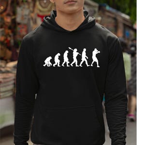 May include: Black hooded sweatshirt with a white graphic depicting the evolution of a boxer. The graphic shows a series of figures, starting with a primate and progressing to a boxer in a fighting stance. The sweatshirt has a front pocket.