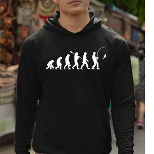 May include: Black hooded sweatshirt with a white graphic depicting the evolution of a fisherman. The graphic shows a series of figures evolving from a primate to a person fishing. The sweatshirt has a front pocket.