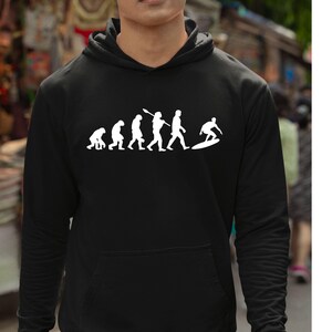May include: Black hooded sweatshirt with a white graphic depicting the evolution of surfing. The graphic shows a series of figures, starting with a primate and ending with a surfer on a board. The sweatshirt has a front pocket.