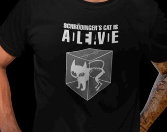 May include: Black t-shirt with a white graphic of a cat in a box. The text "Schrödinger's Cat is ALIVE" is printed on the shirt.