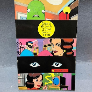 May include: A comic book cover with a collage of colorful illustrations. The title "Like a Velvet Glove Cast in Iron" is in a yellow circle. The artwork features a green alien, a masked man, and a woman smoking a pipe.