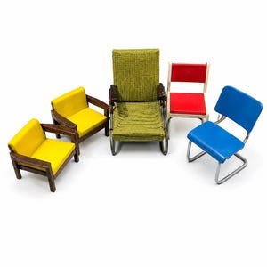Pode incluir: Uma coleção de cinco cadeiras em miniatura, incluindo duas poltronas amarelas com estruturas de madeira escura, uma poltrona central verde texturizada com apoios de braço de madeira escura, uma cadeira vermelha com estrutura branca e uma cadeira azul com estrutura de metal prateado.