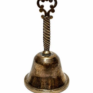 Pode incluir: Uma campainha de mão metálica com acabamento em latão envelhecido. A campainha apresenta uma base alargada e um cabo torcido, semelhante a uma corda, rematado com um ornamento decorativo. A superfície mostra sinais de idade e oxidação.