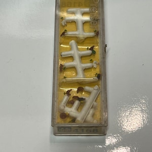 May include: A clear plastic case containing white plastic model trees and small, colourful decorative elements. The case has the word "Preiser" printed on it. The bottom of the case has the number "4168".
