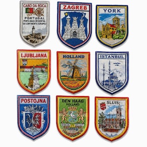 Peut inclure: Un ensemble de neuf écussons brodés en forme de blason disposés sur trois rangées. Chaque écusson représente une ville ou un lieu différent, avec les noms Cabo da Roca, Zagreb, York, Ljubljana, Holland, Istanbul, Postojna, Den Haag et Sluis.