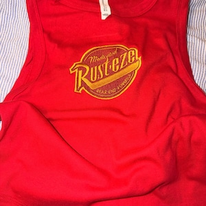 May include: A vibrant red vest top with a crew neck and a large, circular graphic on the front.