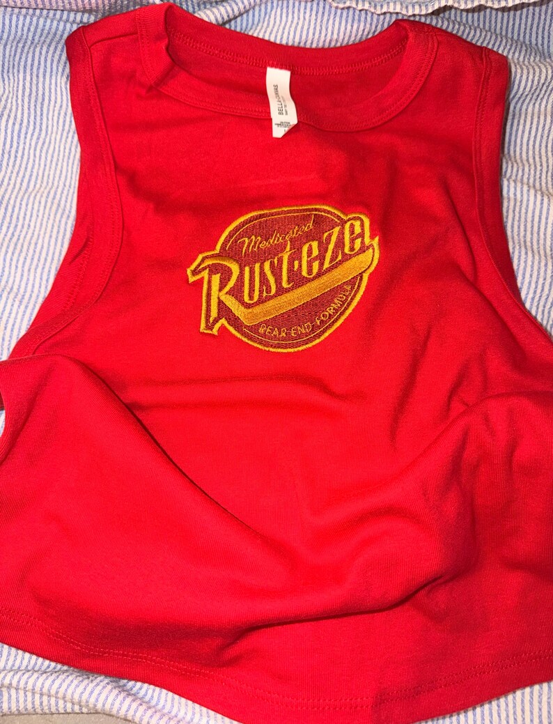 May include: A vibrant red vest top with a crew neck and a large, circular graphic on the front.