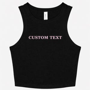 May include: Black crop top with a scoop neck and the text "CUSTOM TEXT" in pink. The top is sleeveless and made of a soft material. The garment is a casual style.