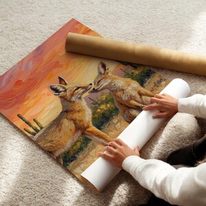 May include: A rectangular art print featuring an oil painting of two coyotes in a desert landscape at sunset. The scene displays textured brushstrokes in shades of orange, yellow, and brown, depicting the animals near cacti and desert flora.
