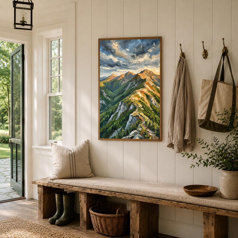 May include: A rectangular framed oil painting depicting a mountain range with green slopes, rocky peaks, and a cloudy sky. The artwork features a vibrant color palette of deep greens, earthy browns, and bright blues, displayed on a white wall.
