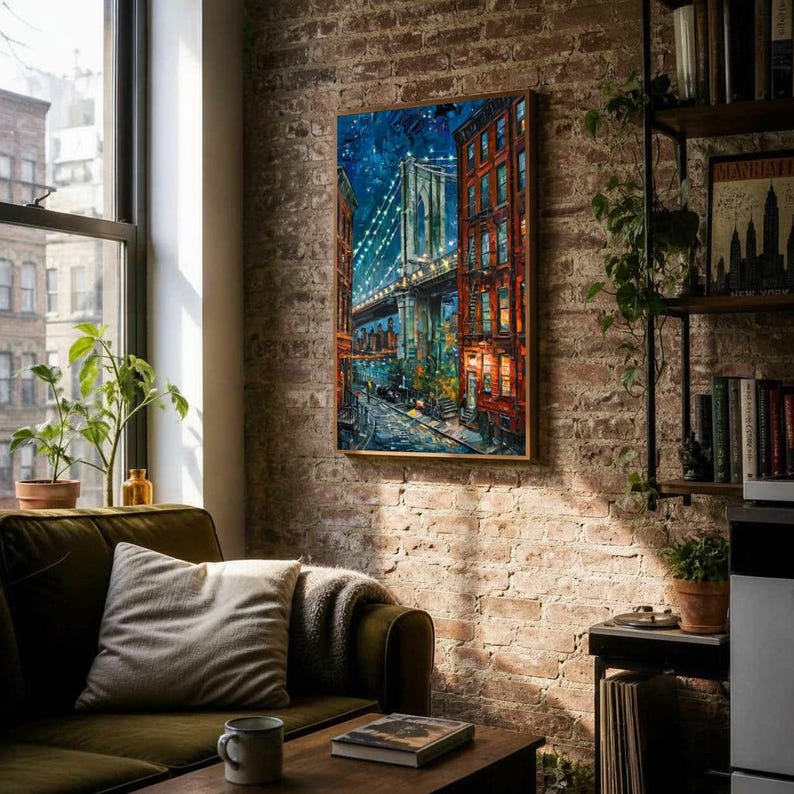 May include: A framed painting of the Brooklyn Bridge at night, with illuminated lights and city buildings. The artwork is displayed on a brick wall in a living room setting, with a sofa, window, and bookshelf.