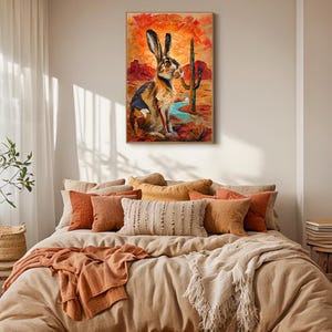 Puede incluir: Una impresi&oacute;n de arte mural rectangular con una pintura al &oacute;leo de una liebre marr&oacute;n sentada en un paisaje des&eacute;rtico. La escena incluye un cactus saguaro alto, formaciones rocosas rojas y un arroyo azul bajo un cielo naranja y amarillo.