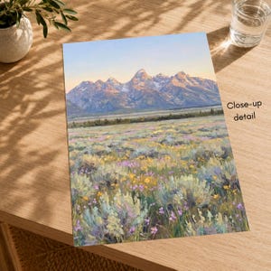 May include: A rectangular art print featuring a landscape painting of a mountain range under a soft sky, with a foreground filled with sagebrush and scattered yellow and purple wildflowers. The text Close-up detail is printed on the right side.
