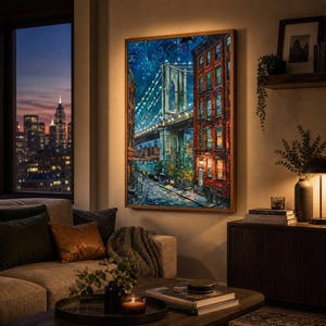 May include: A framed painting of the Brooklyn Bridge at night, with city buildings and streetlights. The artwork features a vibrant color palette of blues, reds, and yellows, creating a warm and inviting atmosphere. The painting is displayed in a living room setting.