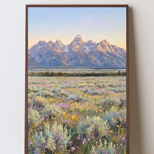 May include: A framed oil painting depicting a mountain range with snow-capped peaks under a soft sunrise sky. The foreground features a vast meadow filled with textured brushstrokes of yellow and purple wildflowers and sage-green shrubs.
