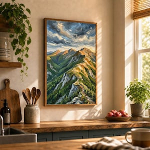 May include: A framed oil painting depicting a mountain range with green slopes, rocky peaks, and a dramatic cloudy sky. The artwork features warm golden light hitting the ridges, contrasting with deep shadows and a vibrant, textured brushstroke style.
