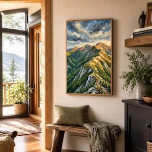 May include: A vertical oil painting on canvas depicting a mountain range with green slopes, rocky peaks, and a dramatic sky with swirling clouds in shades of blue, white, and gold, displayed in a simple wooden frame on a light-colored wall.
