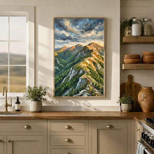 May include: A vertical oil painting depicting a mountain range with green slopes, rocky peaks, and a dramatic sky with swirling clouds in shades of blue, white, and gold, displayed in a kitchen setting above a wooden countertop.