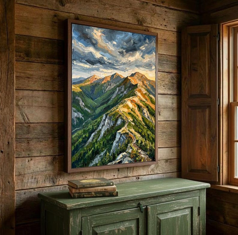 May include: A framed oil painting depicting a mountain range with green slopes, rocky peaks, and a dramatic cloudy sky. The artwork features thick, visible brushstrokes in shades of green, brown, gray, and white, capturing a rugged landscape.