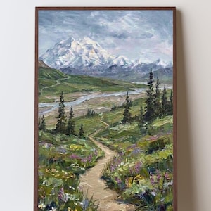 May include: An oil painting in a dark wood frame depicting a landscape with a winding dirt path leading through a green meadow filled with wildflowers toward a distant snow-capped mountain range under a cloudy sky with tall evergreen trees.