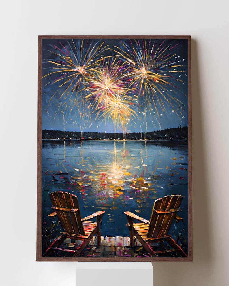 May include: A framed wall art print depicting two wooden Adirondack chairs on a dock overlooking a dark lake at night. Above the water, vibrant yellow, orange, and purple fireworks explode in the sky, with their light reflecting on the water surface.