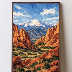 Puede incluir: Pintura al óleo de un paisaje de montaña enmarcada en madera oscura. La obra representa un valle entre formaciones rocosas rojas, que conduce a una montaña nevada bajo un cielo azul con nubes blancas. Es un paisaje.