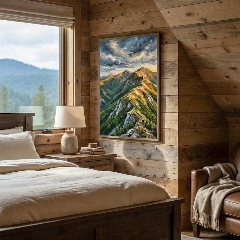 May include: A rectangular wall art print featuring an oil painting of a mountain range with green slopes, rocky peaks, and a dramatic cloudy sky. The artwork is displayed in a vertical orientation on a wooden wall above a bedside table.