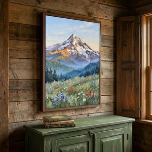 Pu&ograve; includere: Una stampa artistica da parete rettangolare che presenta un dipinto a olio di una vetta innevata che si erge sopra una fitta foresta e un prato vivace pieno di fiori selvatici colorati, tra cui lupini blu e fiori pennello rossi.