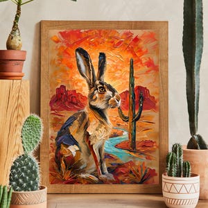 Puede incluir: Una impresi&oacute;n art&iacute;stica enmarcada con una pintura al &oacute;leo estilo impasto de una liebre marr&oacute;n en un paisaje des&eacute;rtico. La escena muestra un vibrante atardecer naranja y rojo, un cactus saguaro alto y un arroyo azul serpenteante.