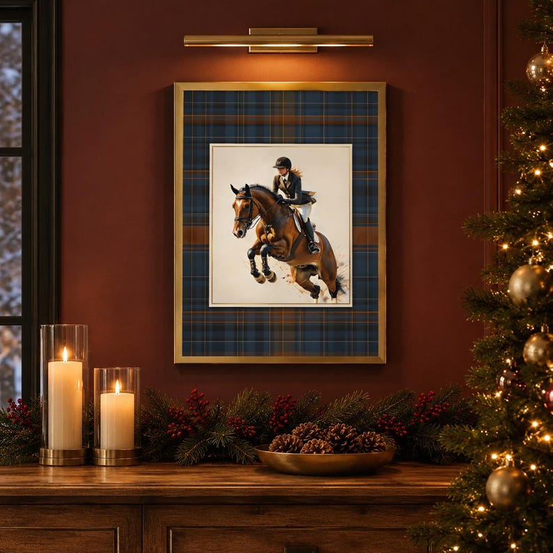 May include: A framed wall art print featuring a brown horse jumping with a rider in equestrian gear. The artwork is set against a dark blue and brown plaid background within a gold frame, displayed on a wall with a light fixture above it.