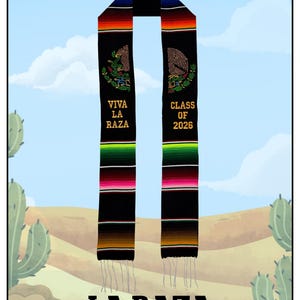 May include: Black graduation sash with colorful stripes and the text "VIVA LA RAZA" and "CLASS OF 2026". The sash features an embroidered eagle design and is trimmed with tassels. The background shows a desert scene with cacti.