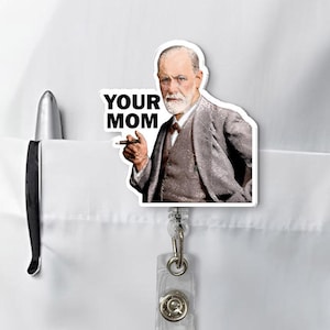 Puede incluir: Un portatarjetas blanco con una imagen de Sigmund Freud con el texto "YOUR MOM". El portatarjetas est&aacute; sujeto a un bolsillo de camisa blanco, junto a un bol&iacute;grafo.