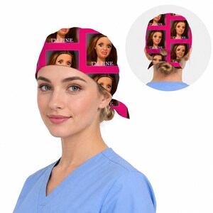 Peut inclure: Une charlotte de bloc op&eacute;ratoire avec un motif r&eacute;p&eacute;titif repr&eacute;sentant un visage de poup&eacute;e aux cheveux bruns et le texte I'M FINE. Le design est sur un fond rose vif avec des lignes de grille rose fonc&eacute;. La charlotte se noue &agrave; l'arri&egrave;re.