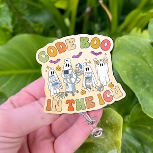 May include: A badge reel with a Halloween-themed design. The badge features the text "CODE BOO IN THE ICU" in orange, green, and yellow. The design includes cartoon ghosts, pumpkins, and bats.