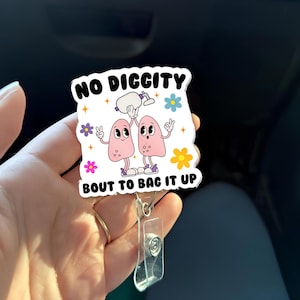 Könnte beinhalten: Ein weißes Ausweis-Jojo mit dem Text "NO DIGGITY" und "BOUT TO BAG IT UP". Das Abzeichen zeigt zwei Cartoon-Lungen mit Armen und Beinen, die eine Flasche halten. Bunte Blumen und Sterne umgeben den Text und die Lungen.