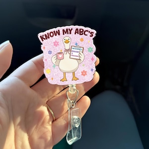 May include: A badge reel with a cartoon goose holding a mug and a sign that reads "Antecedents, Behaviors & Consequences." The badge reel has the text "Know My ABC's" and is decorated with colorful stars and flowers.