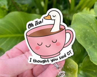 May include: A pink badge reel sticker featuring a cartoon teacup with a goose neck and head emerging from the tea. The text "Oh Tea!" is above the cup, and "I thought you said OT" is below.