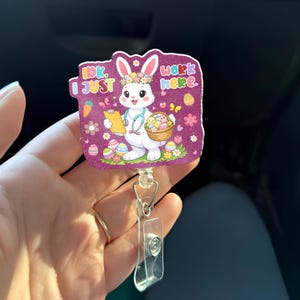 May include: A purple badge reel featuring a cartoon bunny with a flower crown, clipboard, and stethoscope. The bunny is surrounded by flowers and Easter eggs. Text on the badge reads "Idk. I just work here."