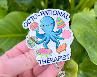 Könnte beinhalten: Ein Abzeichen mit einem blauen Oktopus, der farbenfrohes Spielzeug und einen Laptop hält. Der Text "OCTO-PATIONAL THERAPIST" ist blau dargestellt. Das Abzeichen hat einen glitzernden Hintergrund und eine einziehbare Rolle.