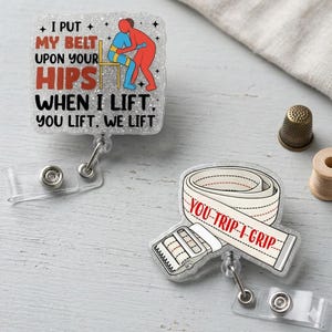 May include: Two glittery badge reels with weightlifting-themed designs. One features text "I PUT MY BELT UPON YOUR HIPS WHEN I LIFT. YOU LIFT, WE LIFT" and an illustration of two figures. The other says "YOU-TRIP-I-GRIP" with a weightlifting belt.