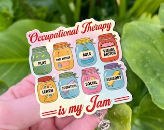 Puede incluir: Una insignia colorida con el texto "Occupational Therapy" y la frase "is my Jam". Muestra frascos etiquetados con términos como "Play", "Fine Motor" y "Social". La insignia tiene un carrete retráctil de plástico transparente.