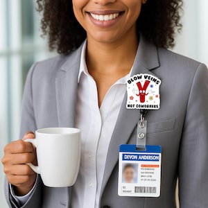 May include: A white badge reel with a cartoon image that says "BLOW VEINS NOT COWORKERS". The badge reel is attached to a blue and white ID badge that says "DEVON ANDERSON". The person is wearing a gray blazer and holding a white mug.