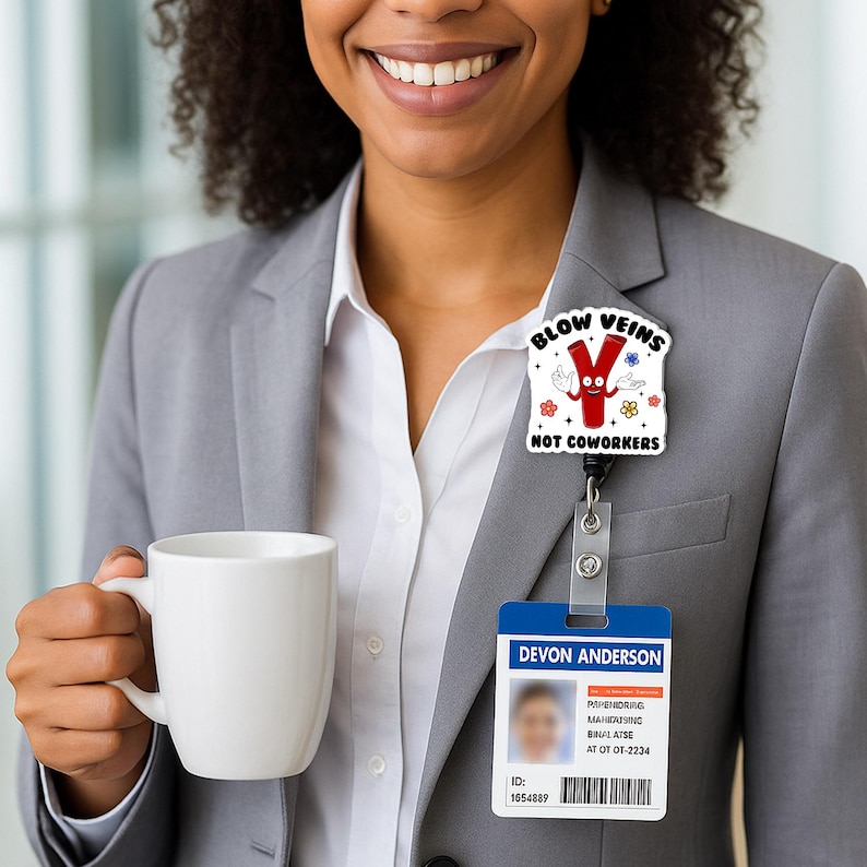 May include: A white badge reel with a cartoon image that says "BLOW VEINS NOT COWORKERS". The badge reel is attached to a blue and white ID badge that says "DEVON ANDERSON". The person is wearing a gray blazer and holding a white mug.
