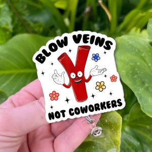 May include: A white badge with the text "BLOW VEINS NOT COWORKERS" features a cartoon vein character with a smiling face and arms. The badge has a retractable reel clip.