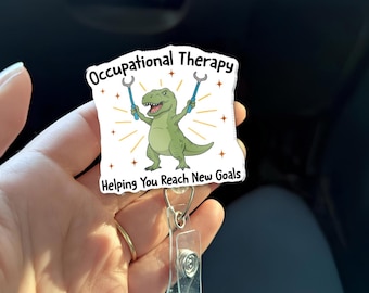 Könnte beinhalten: Ein weißes Ausweis-Jojo mit den Worten "Occupational Therapy" und "Helping You Reach New Goals". Das Abzeichen zeigt einen grünen Cartoon-Dinosaurier, der blaue Werkzeuge hält, mit einem goldenen Sternmuster.