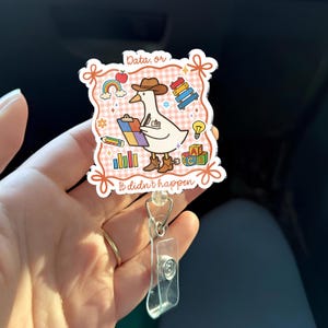 May include: A white badge reel with a cartoon goose wearing a cowboy hat and boots, holding a clipboard. The badge has the text "Data, or It didn't happen" and features a rainbow, apple, and other graphics.