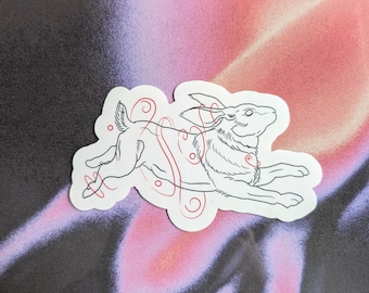 May include: A white sticker with a line drawing of a rabbit running with red swirls around it.