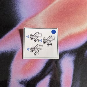 Könnte beinhalten: Eine weiße Karte mit drei schwarz-weißen Bienenillustrationen und blauen Punkten. Die Bienen fliegen und haben Flügel. Die Karte hat einen blauen Punkt in der oberen rechten Ecke.