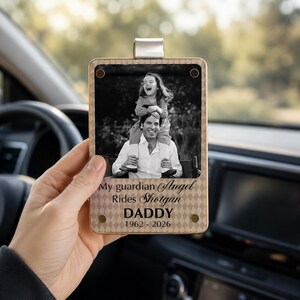 Peut inclure: Un ornement rectangulaire à suspendre avec une bordure à motif losange beige. Il présente une photographie en noir et blanc d'un enfant assis sur les épaules d'une personne, avec le texte : My guardian Angel Rides Shotgun DADDY 1962 - 2026.