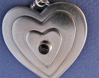 Three tiered sterling silver heart pendant with faceted garnet